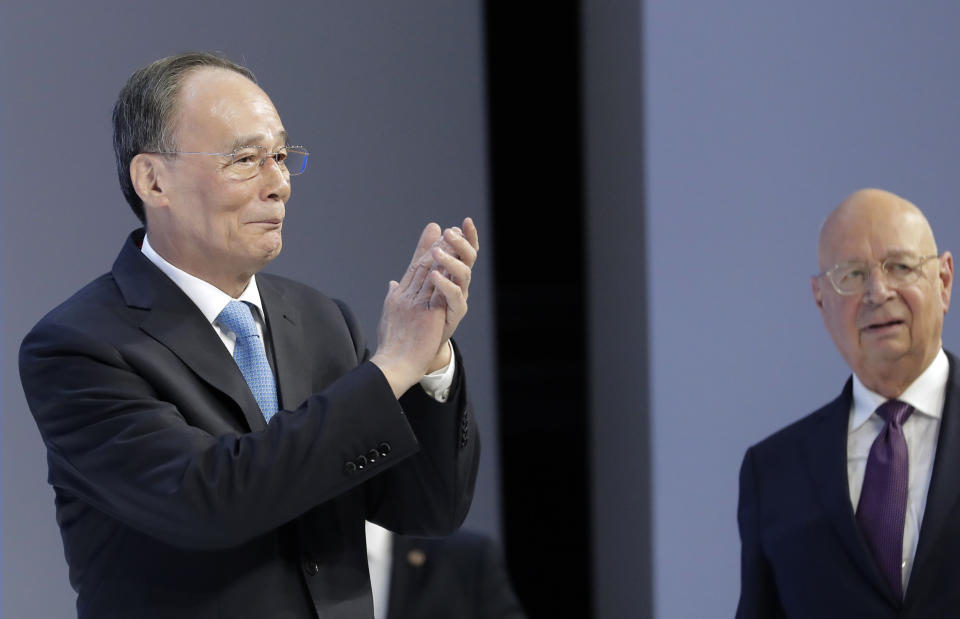 Chinese Vice President Wang Qisan applauds as he enters the stage with Klaus Schwab, founder and Executive Chairman of the World Economic Forum, at the annual meeting of the World Economic Forum in Davos, Switzerland, Wednesday, Jan. 23, 2019. (AP Photo/Markus Schreiber)