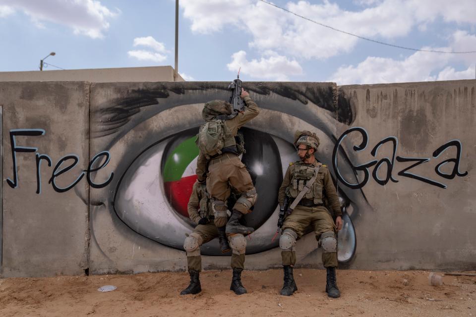 Israeli soldiers climb on a wall as they conduct a mock assault during an urban warfare exercise at an army training facility, in Zeelim army base, southern Israel, Jan. 24, 2022.