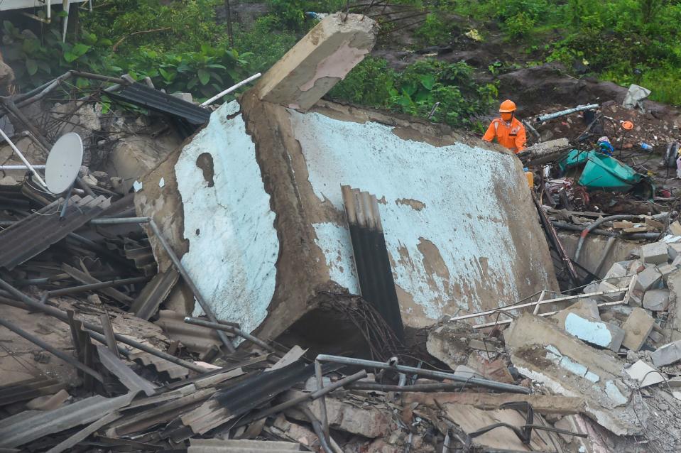 A rescue worker searches for people in the rubble of a five-storey apartment building after it collapsed in Mahad. (Photo by PUNIT PARANJPE/AFP via Getty Images)