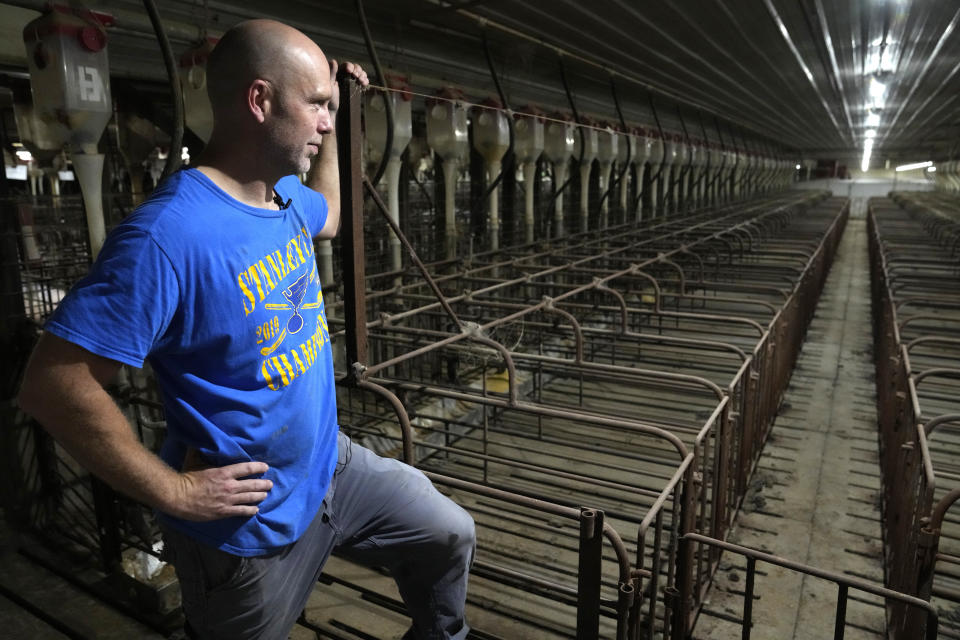 Jared Schilling stands at the end of a row of narrow gestation crates he no longer uses on his sow farm Thursday, June 29, 2023, in Walsh, Ill. Schilling has made his farm compliant with a California law, taking effect on July 1, that promises to get breeding pigs out of narrow cages that restrict their movement by building larger breeding areas with more room for his sows to move.(AP Photo/Jeff Roberson)