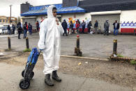 In this March 25, 2020, photo, Cire Wilson, 12, wears a protective suit due to worries from his mother about coronavirus, as he waits for a bag of fresh produce during a delivery of food donations in southeast Washington. Though Wilson said his mother had reserved a bag there were none left for them after dozens of people came out for the food. Local volunteers are the tip of the spear for a grassroots community effort to keep Washington's most vulnerable neighborhoods fed during the unprecedented coronavirus crisis which has nearly shut down the American economy. (AP Photo/Jacquelyn Martin)