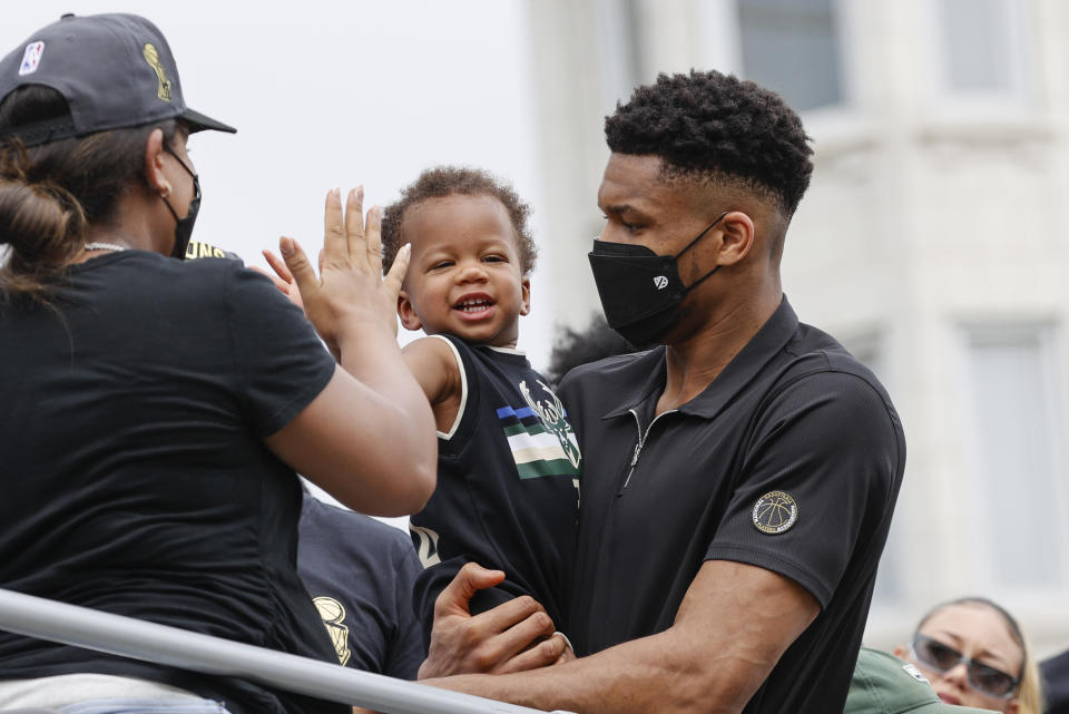 Milwaukee Bucks' Giannis Antetokounmpo, right, girlfriend Mariah Riddlesprigger and their son Liam ride on a bus during a parade for the NBA Championship Bucks basketball team Thursday, July 22, 2021, in Milwaukee. (AP Photo/Jeffrey Phelps)