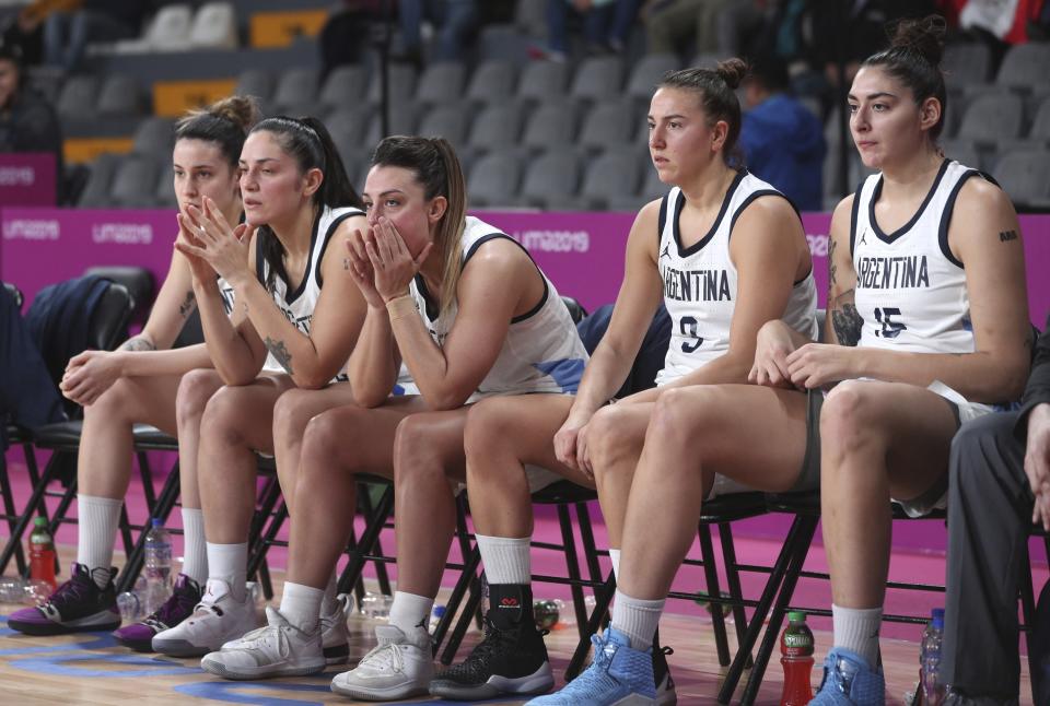 ADDS REASON WHY ARGENTINA IS OUT OF THE MEDAL ROUND - Argentina's players watch the women's basketball match against the Virgin Islands from the bench, at the Pan American Games in Lima, Peru, Thursday, Aug. 8, 2019. Argentina's women's basketball team had to forfeit its match against Colombia at the Pan American Games on Wednesday for wearing the wrong uniform color. Argentina won today’s match against the Virgin Islands but is out of the medal rounds because of the uniform blunder. (AP Photo/Martin Mejia)