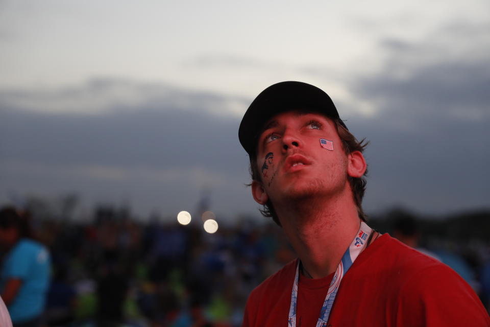 A young man waits for the arrival of Pope Francis at the metro park Campo San Juan Pablo II, as dawn breaks in Panama City, Sunday, Jan. 27, 2019. Francis is wrapping up his trip to Central America with a final World Youth Day Mass and a visit to a church-run home for people living with AIDS. (AP Photo/Rebecca Blackwell)