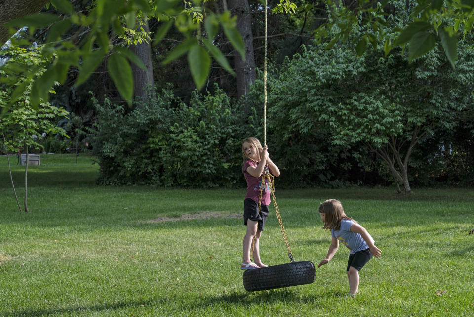 Maggie and McKenzie Whitlock play on their tire swing at home. (Sarah Rice / for NBC News)