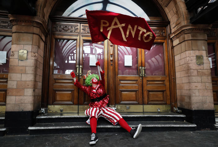 An actor dressed as pantomime dame waves a flag at the entrance of a theatre before marching on Parliament to demand more support for the theatre sector amid the COVID-19 pandemic, in London, Wednesday, Sept. 30, 2020. (AP Photo/Frank Augstein)