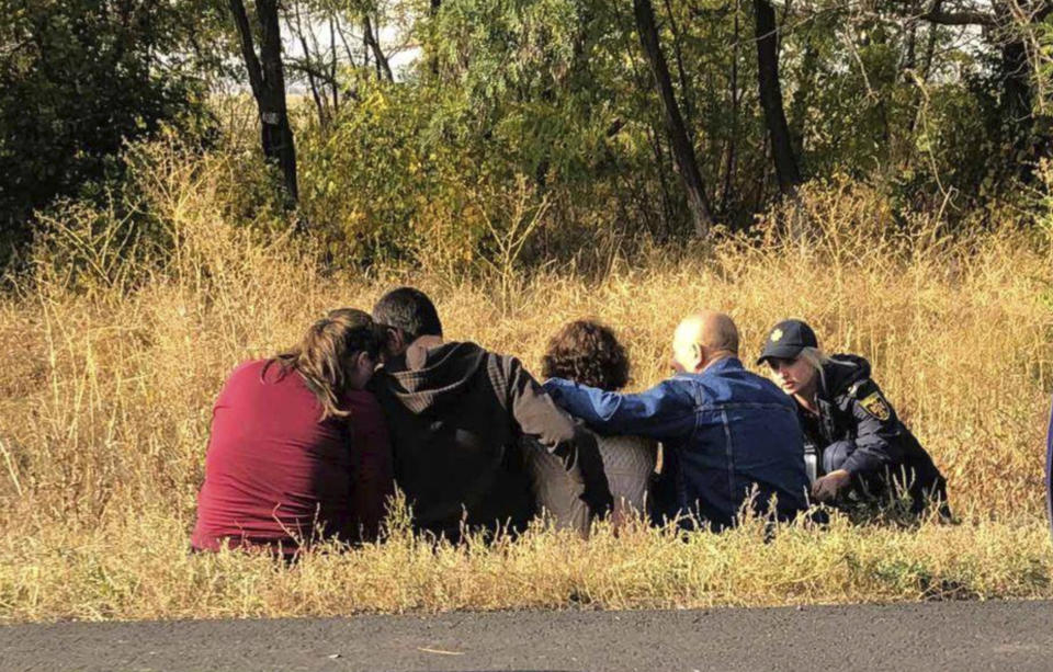 In this photo provided by the Emergency Situation Ministry, relatives of crash victims mourn at the scene where an AN-26 military plane crashed in the town of Chuguyiv close to Kharkiv, Ukraine, Saturday, Sept. 26, 2020. The Ukrainian military plane carrying students at an aviation school crashed and burst into flames while landing late Friday. (Emergency Situation Ministry via AP)