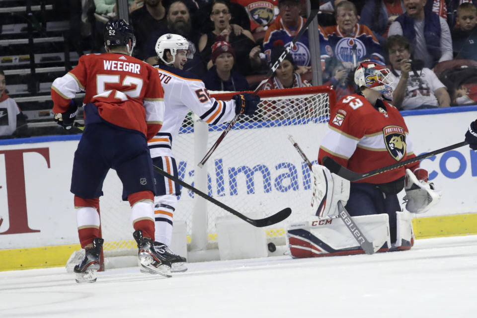 The puck gets past Florida Panthers goaltender Sam Montembeault (33) on a goal scored by Edmonton Oilers defenseman Adam Larsson, not shown, as right wing Kailer Yamamoto (56) looks on during the first period of an NHL hockey game, Saturday, Feb. 15, 2020, in Sunrise, Fla. (AP Photo/Lynne Sladky)