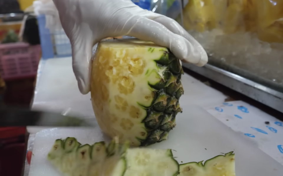 A pineapple is getting cut