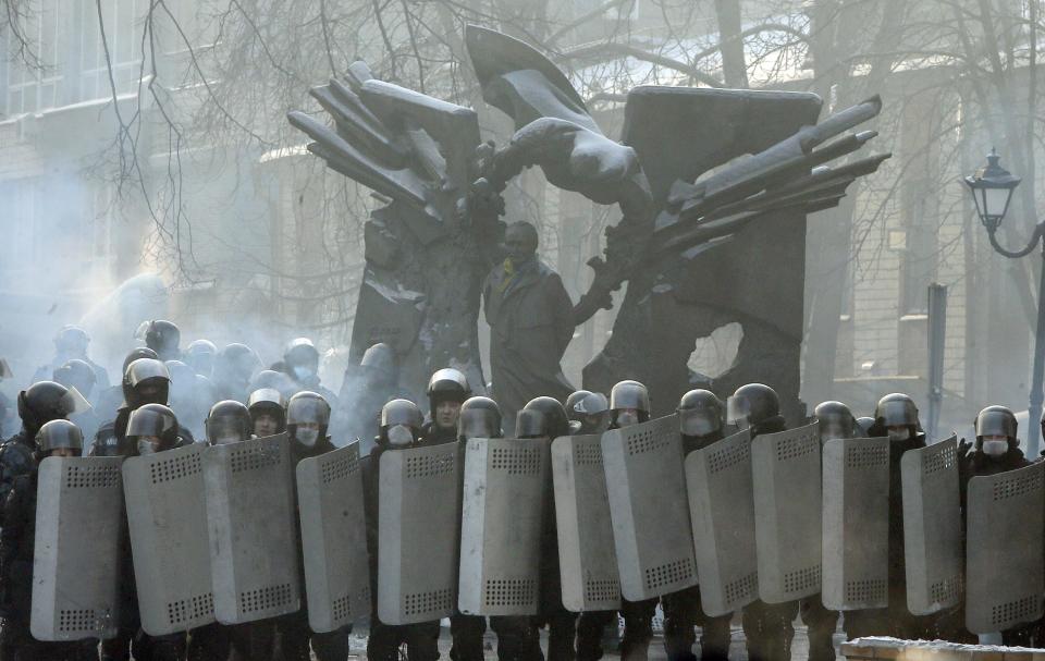 Riot police officers block a street in front of barricades of protesters at the monument to Viacheslav Chornovil, a prominent politician in Ukraine and a former Soviet political prisoner, in central Kiev, Ukraine, Friday, Jan. 24, 2014. Protesters have seized a government building in the Ukrainian capital while also maintaining the siege of several governors' offices in the country's west, raising the pressure on the government. After meeting with President Viktor Yanukovych on Thursday, opposition leaders told the crowds that he has promised to ensure the release of dozens of protesters detained after clashes with police and stop further detentions. (AP Photo/Efrem Lukatsky)