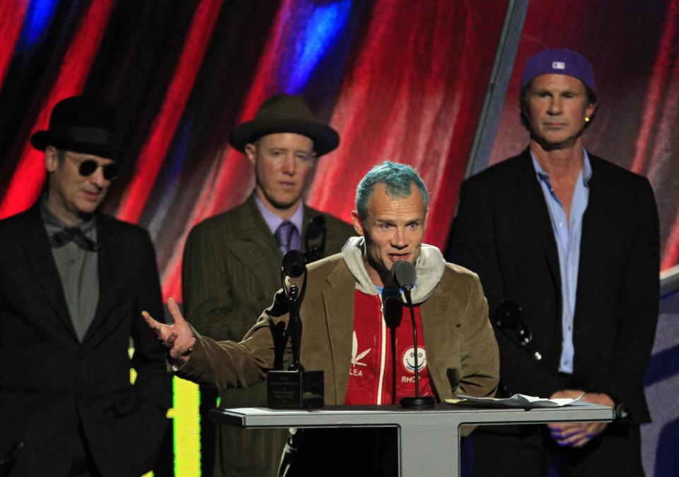 Red Hot Chili Peppers' Mike "Flea" Balazary speaks after induction into the Rock and Roll Hall of Fame Sunday, April 15, 2012, in Cleveland. Former drummers Cliff Martinez, far left, and Jack Irons, join current drummer Chad Smith, right. (AP Photo/Tony Dejak)