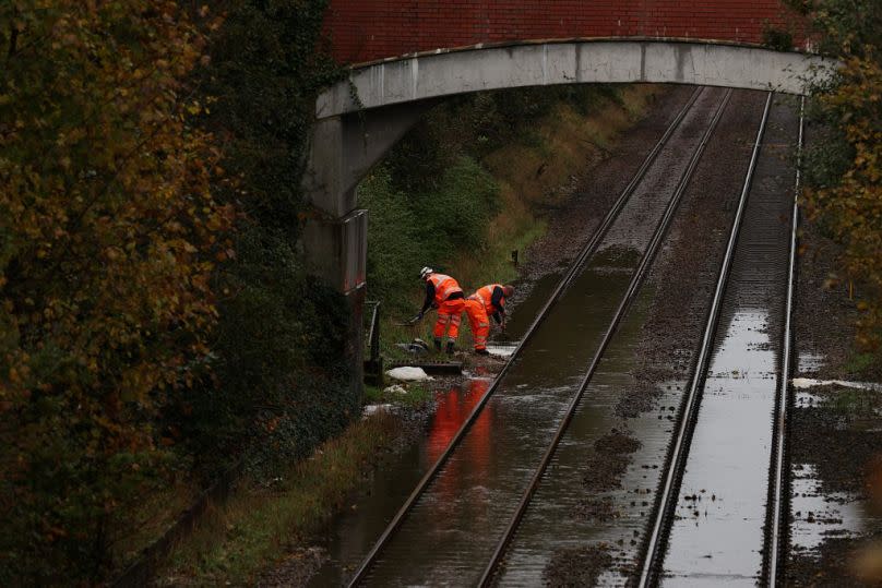 Workers try to clear water on a flooded railway line in Romsey, southern England, on November 2, 2023.