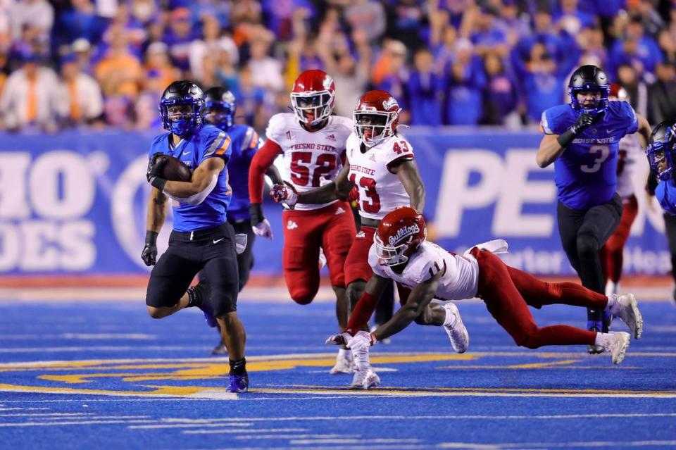 Boise State running back George Holani (24) runs past the diving tackle attempt by Fresno State defensive back Cale Sanders Jr. (11) on a 59-yard run during the first half of an NCAA college football game Saturday, Oct. 8, 2022, in Boise, Idaho. (AP Photo/Steve Conner)