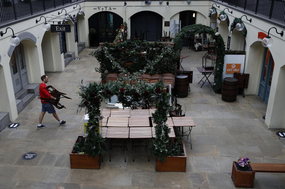 An owner of a restaurant starts preparing the outdoor seating for the reopening at Covent Garden in London, Tuesday, June 30, 2020. Tuesday marked 100 days since Britain's Prime Minister Boris Johnson detailed a short list of reasons why individuals could leave their homes as he ordered the immediate closure of all shops selling non-essentials. (AP Photo/Frank Augstein)