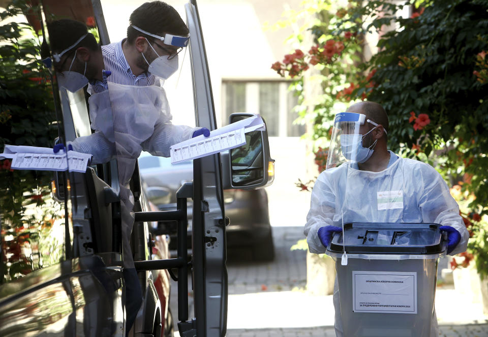 Members of a special election team with a ballot box and voting material check a list of voters who have tested positive for COVID-19 or are in self-isolation, in Skopje, North Macedonia, Monday, July 13, 2020. North Macedonia holds its first parliamentary election under its new country name this week, with voters heading to the polls during an alarming spike of coronavirus cases in the small Balkan nation. Opinion polls in the run-up to Wednesday’s vote indicate a close race between coalitions led by the Social Democrats and the center-right opposition VMRO-DPMNE party. (AP Photo/Boris Grdanoski)