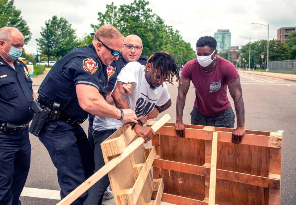 Skip Gibbs, organizer with the Other America Movement, protects the wooden pallets used to block the road in front of the Durham Police Department headquarters before officers arrested him and three others, on Thursday, Jun. 25, 2020, in Durham, N.C. The photo took first place for spot photography among the state’s mid-sized newspapers in the North Carolina Press Association’s annual awards.