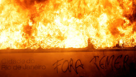 A bus burns during clashes between demonstrators and riot police in a protest against President Michel Temer's proposal reform of Brazil's social security system during general strike in Rio de Janeiro, Brazil, April 28, 2017. The writing reads: "Out Temer." REUTERS/Ricardo Moraes