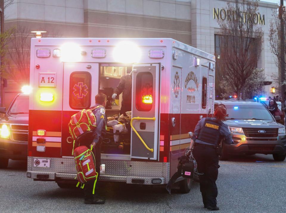 An apparent victim of gunfire receives medical attention before being taken away by ambulance as police, fire and medical personnel respond in force to the food court entrance at the Christiana Mall after a shooting Saturday evening, April 8, 2023.