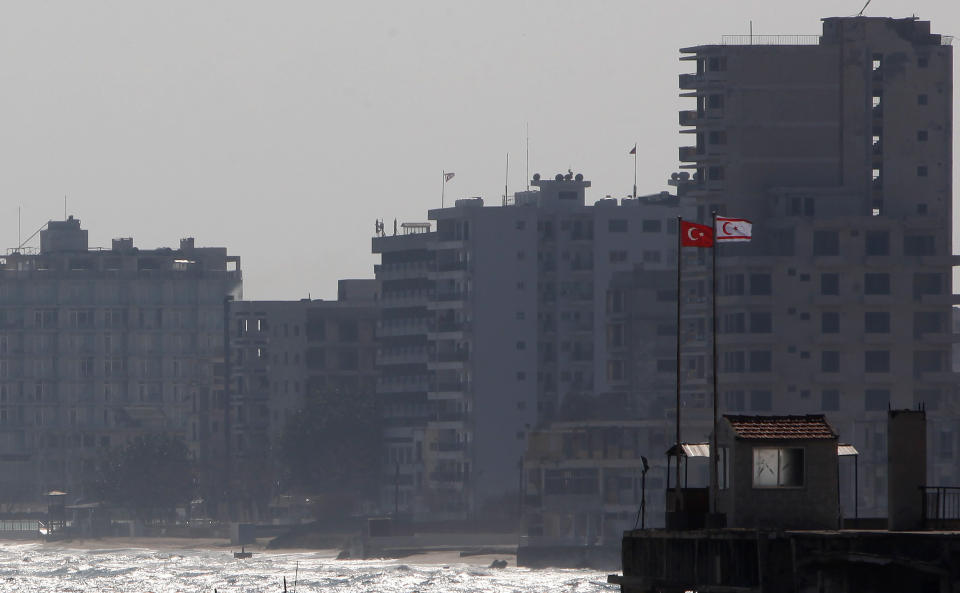 Turkish and Turkish Cypriot breakaway flags are seen on a military guard post in front of the deserted hotels in an area used by the Turkish military in the Turkish occupied area, in the abandoned coastal city of Varosha in Famagusta, southeast Cyprus, Friday, Jan. 17, 2014. The town's crumbling, war-scarred beachfront hotels have become an emblem of the country's division between Turks and Greeks. In 40 years, few have set foot inside the town, which remains heavily guarded by the Turkish army and twists of barbed wire. (AP Photo/Petros Karadjias, file)