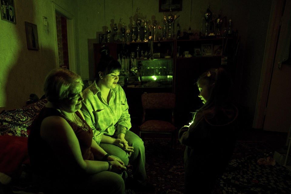 Vasilisa plays with a flashlight with her mother, Polina Ihrak, and grandmother, Svitlana Halinicheva, after returning home from a boxing tournament in honor of her father Maksym Halinichev, who was killed during fighting with Russian forces in March 2023, in Shostka, Sumy region, Ukraine on Sunday, Feb. 4, 2024. (AP Photo/Evgeniy Maloletka)