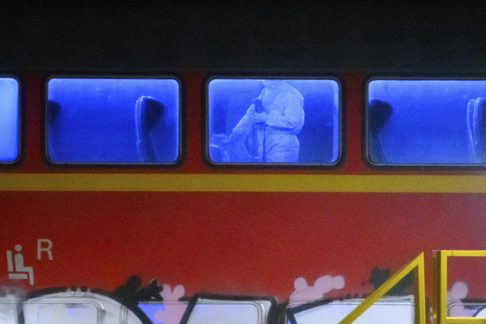 An investigator in a white protective suit works in the regional train that had been driven onto a siding in Neumunster, Germany, Wednesday, Jan. 25, 2023. A knife-wielding man described as a stateless Palestinian has fatally stabbed several people and injured others on a train in northern Germany before being grabbed by passengers and arrested by police, officials said. The motive of Wednesday's attack was not immediately known. (Jonas Walzberg/dpa via AP)