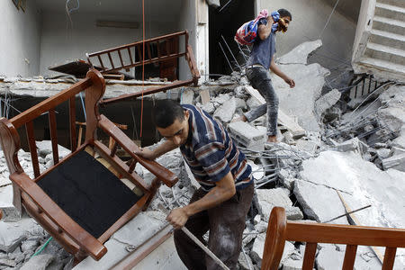 Men salvage belongings from the ruins of a home that residents say was hit by an Israeli air strike in Gaza City August 9, 2014. REUTERS/Siegfried Modola
