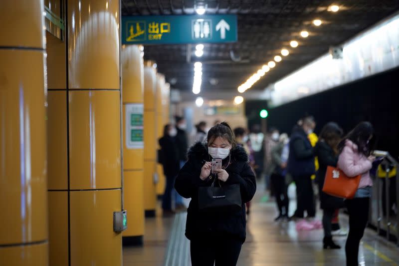 People wear masks as they wait for their train at a subway station in Shanghai