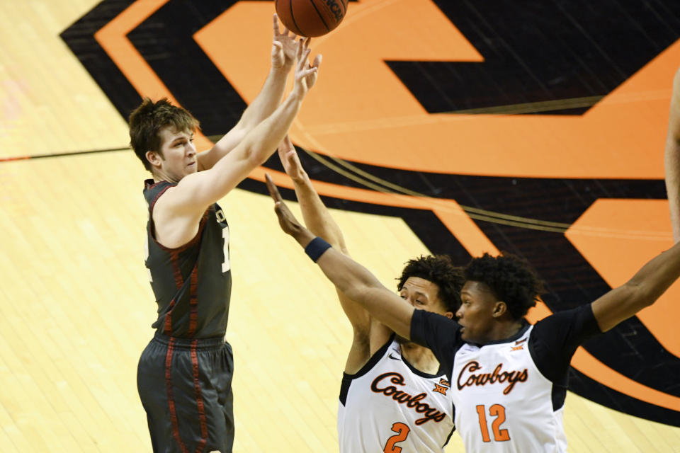 Oklahoma guard Alondes Williams (15) shoots while under pressure from Oklahoma State guard Cade Cunningham (2) and forward Matthew-Alexander Moncrieffe (12) during an NCAA college basketball game Monday, March 1, 2021, in Stillwater, Okla. (AP Photo/Brody Schmidt)