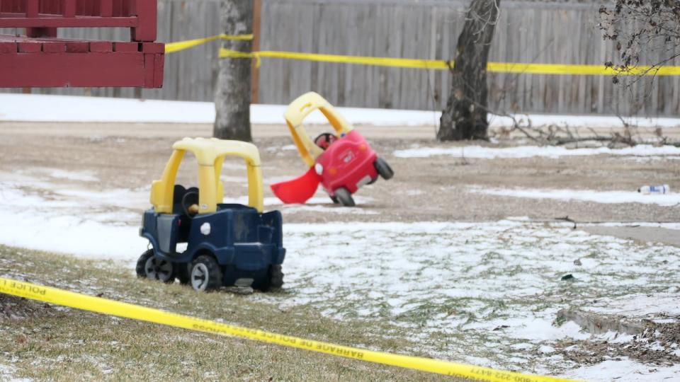 Children's toys are seen in a yard in Carman on Monday, surrounded in yellow police tape.
