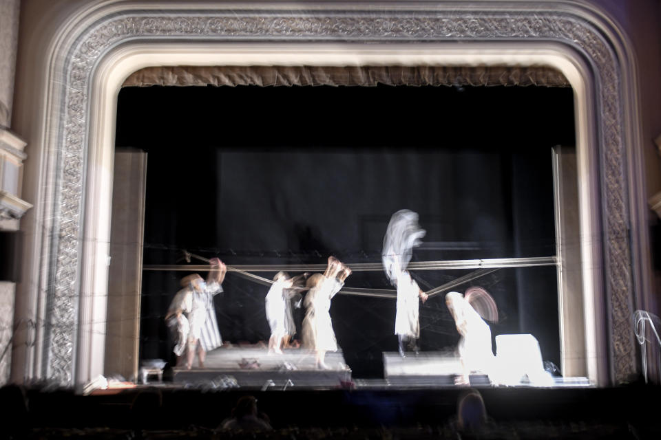 In this photograph shot with a slow shutter speed actresses of the Jewish State Theatre, wearing face masks for protection against COVID-19 infection, perform during rehearsals for the premiere of the "The Beautiful Days of My Youth" play, based on the diary of Romanian Jewish Holocaust survivor Ana Novac, in Bucharest, Thursday, Oct. 15, 2020. The latest première at the Jewish State Theater in the Romanian capital, Bucharest, explores the horrors of the Holocaust via a survivor's memories of the Auschwitz and Plaszow concentration camps. (AP Photo/Andreea Alexandru)