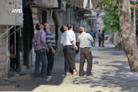 This photo provided by the anti-government activist group Aleppo Media Center (AMC), which has been authenticated based on its contents and other AP reporting, shows Syrian citizens looking up to the sky as they follow a government forces warplane, in Aleppo, Syria, Sunday April 20, 2014. (AP Photo/Aleppo Media Center, AMC)