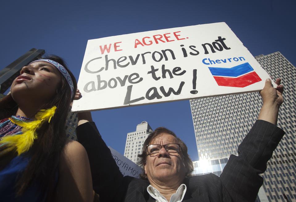 A protester holds up a sign as he demonstrates against Chevron’s Racketeer Influenced and Corrupt Organizations (RICO) trial in New York, October 15, 2013. REUTERS/Carlo Allegri