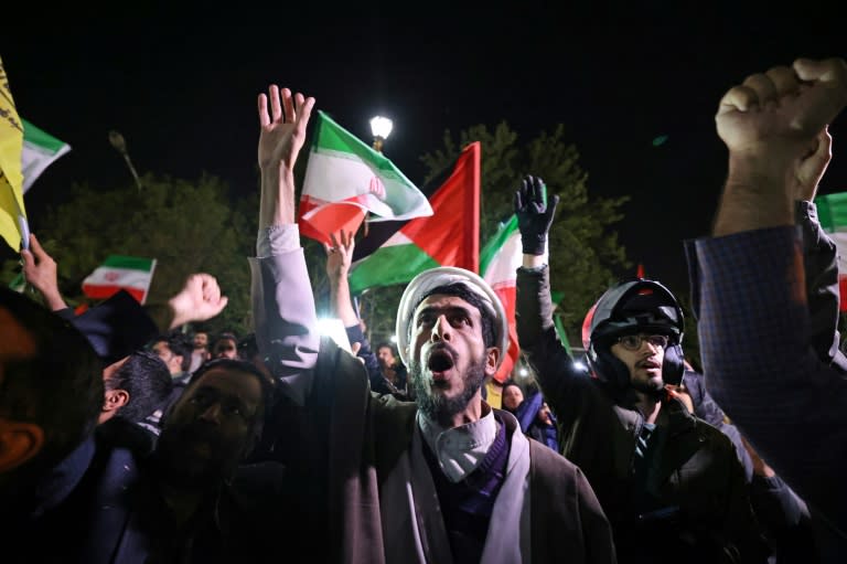 Manifestantes ondean banderas iraníes y palestinas frente a la embajada del Reino Unido en Teherán, el 14 de abril de 2024, tras el ataque con drones y misiles lanzado contra Israel (ATTA KENARE)