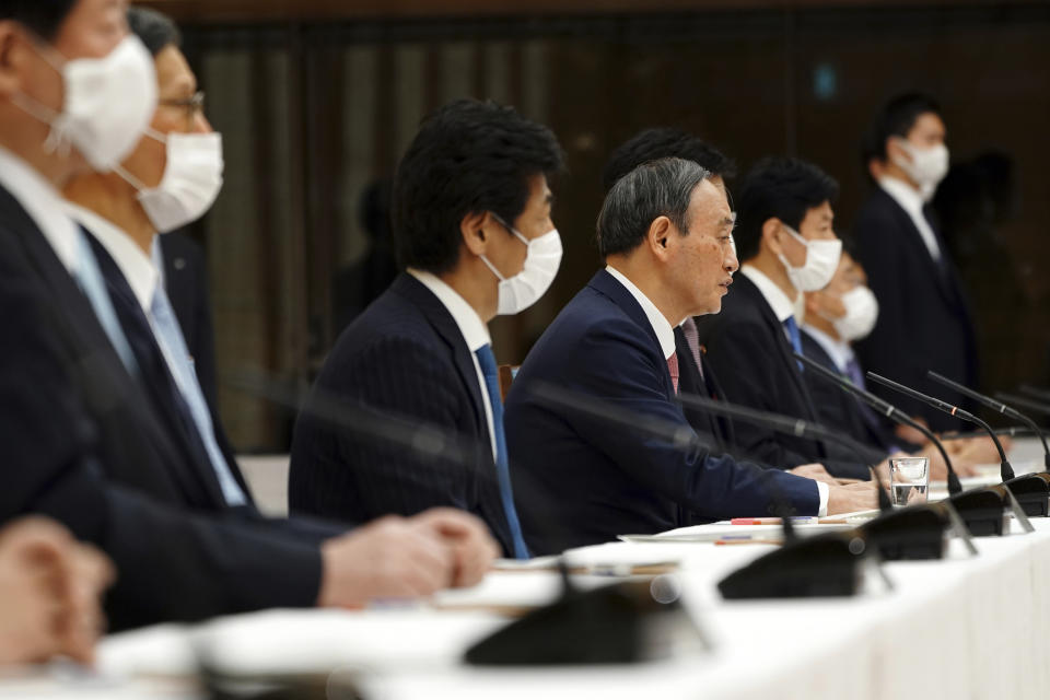Japanese Prime Minister Yoshihide Suga, center right, attends a government task force meeting for the COVID-19 measures at the prime minister's office Friday, April 9, 2021, in Tokyo. Japan announced Friday that it will raise the coronavirus alert level in Tokyo to allow tougher measures to curb the rapid spread of a more contagious variant ahead of the Summer Olympics. (AP Photo/Eugene Hoshiko, Pool)