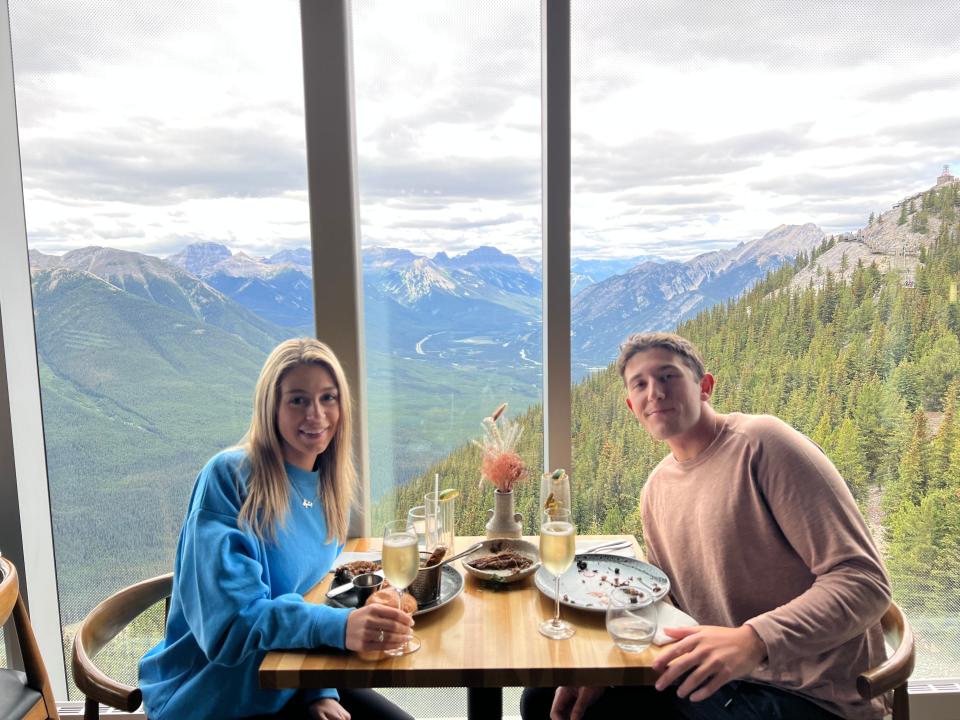 The writer and her boyfriend eating lunch in front of gorgeous window views of the Rocky Mountains