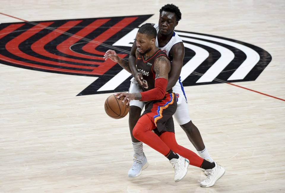 Portland Trail Blazers guard Damian Lillard, left, is fouled by Detroit Pistons forward Sekou Doumbouya during the first half of an NBA basketball game in Portland, Ore., Saturday, April 10, 2021. (AP Photo/Steve Dykes)