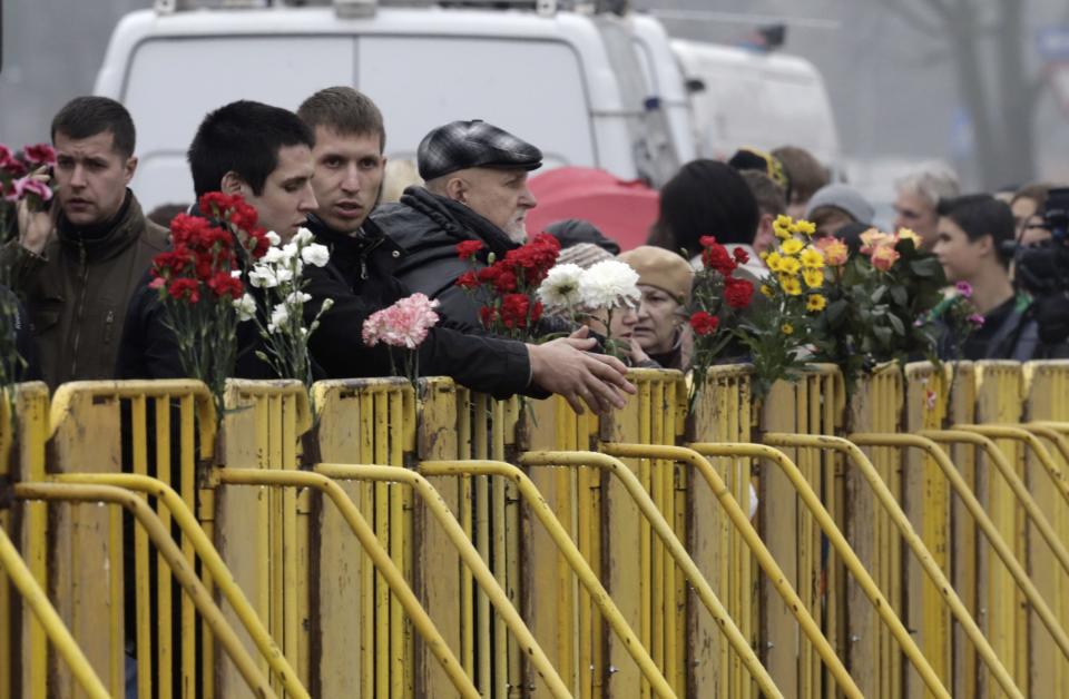 People gather near flowers placed near a collapsed supermarket in capital Riga