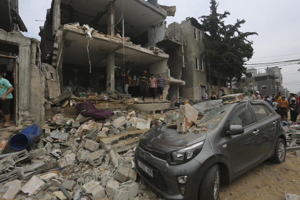 Palestinians stand around a building destroyed in the Israeli bombardment of the Gaza Strip in Rafah, Sunday, Oct. 29, 2023. (AP Photo/Hatem Ali)