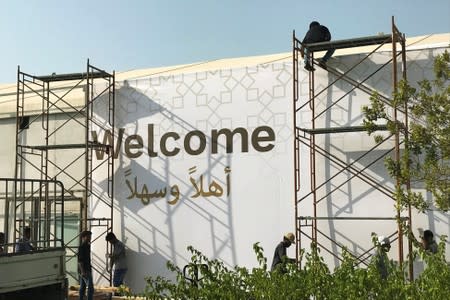 Workers place a banner at the pavilion where the U.S. hosted event "Peace to Prosperity" takes place outside Four Seasons Hotel in Manama