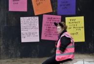 A performer sits in front of signs at 'Dismaland', a theme park-styled art installation by British artist Banksy, at Weston-Super-Mare in southwest England, Britain, August 20, 2015. REUTERS/Toby Melville