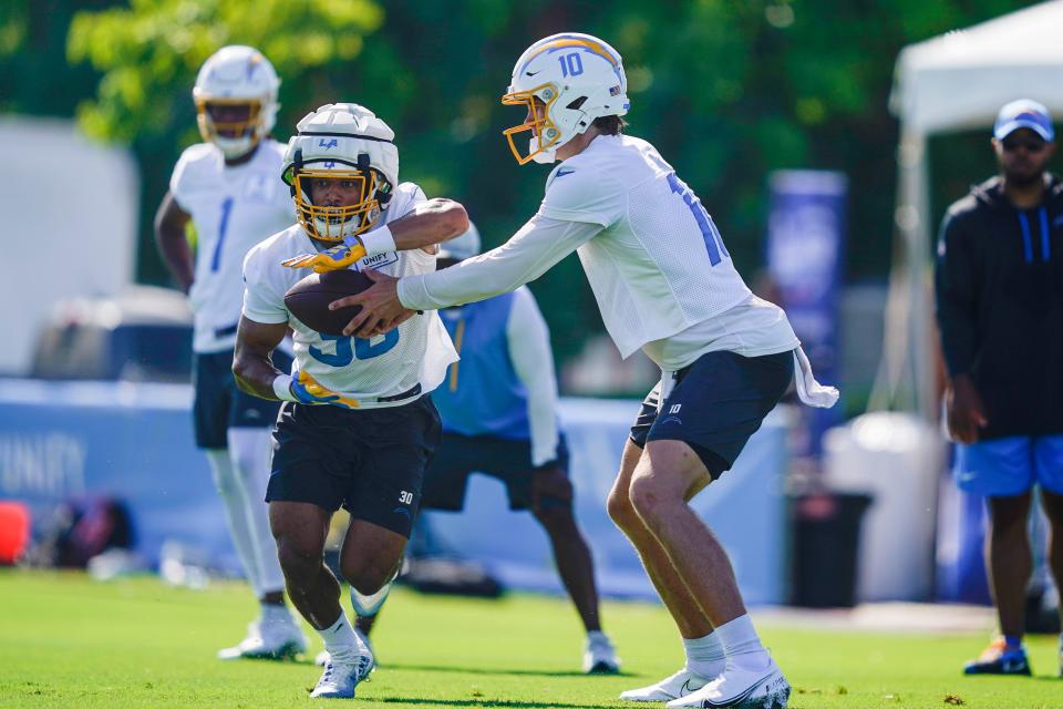 Chargers quarterback Justin Herbert hands off the ball to running back Austin Ekeler during training camp. The Chargers will rely on both to fuel an offense that ranked ninth overall last season.