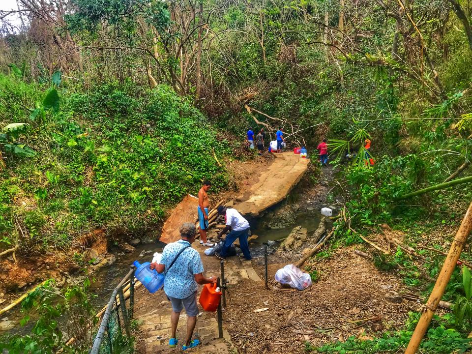 <p>People bath and collect water from a stream in Bayamon, Puerto Rico. (Photo: Caitlin Dickson/Yahoo News) </p>