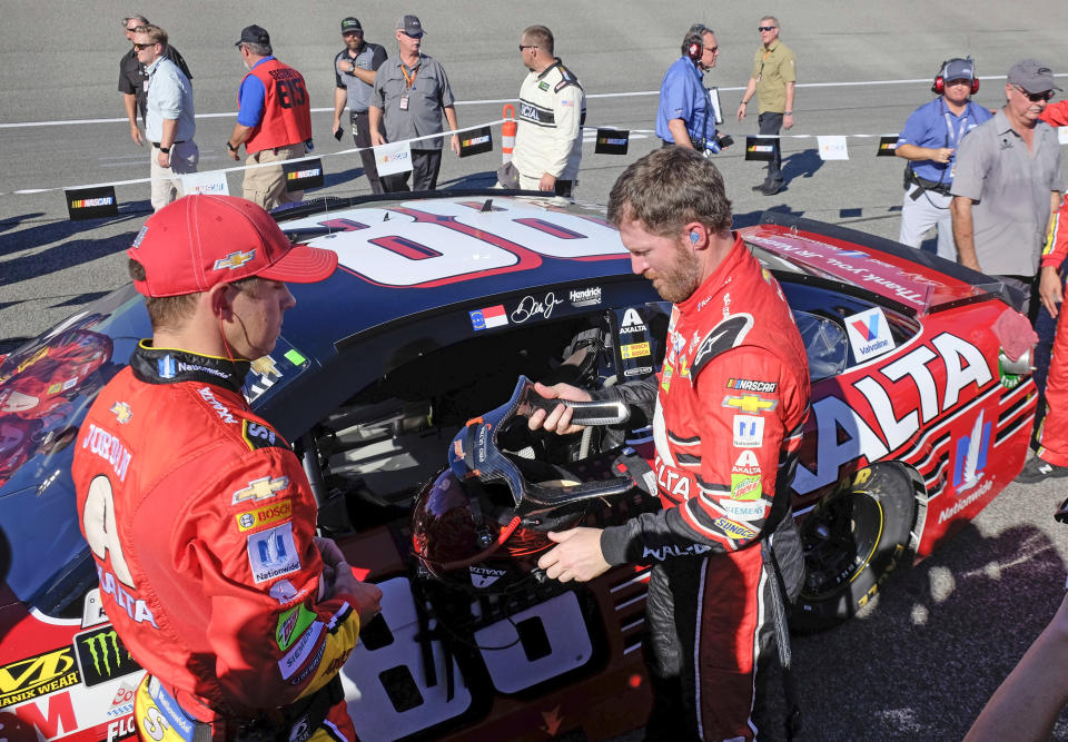FILE - In this Nov. 19, 2017, file photo, Dale Earnhardt Jr., front right, prepares to climb into his race car before a NASCAR Cup Series auto race at Homestead-Miami Speedway in Homestead, Fla. Dale Earnhardt Jr. is returning to the track Saturday, June 13, 2020, getting behind the wheel for an Xfinity race at Homestead-Miami Speedway -- the place where his Cup Series career ended three years ago. (AP Photo/Gaston De Cardenas, File)