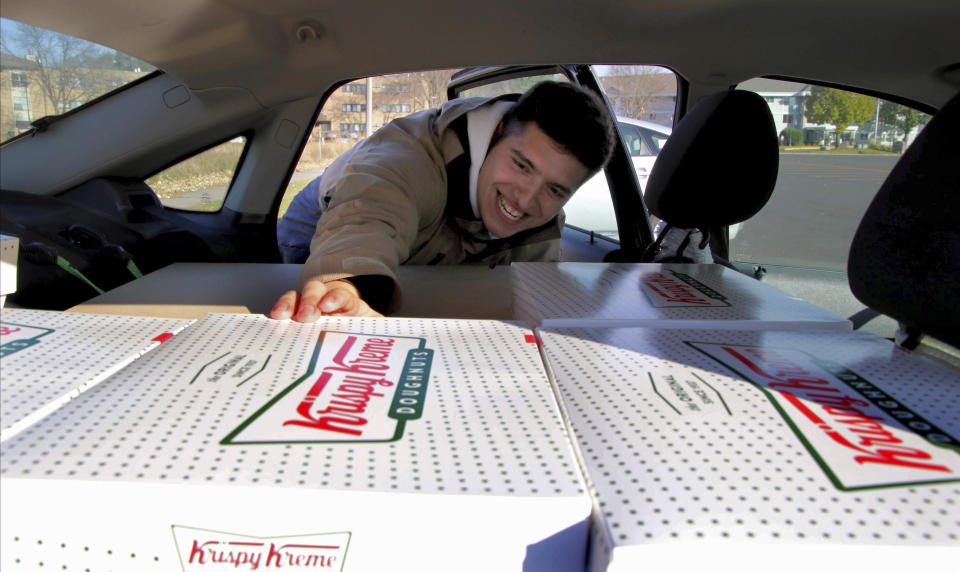 In this Saturday, Oct. 26, 2019 photo, Jayson Gonzalez reaches into his car for another box of Krispy Kreme doughnuts for customers in Little Canada, Minn, who ordered online. Gonzalez, a Minnesota college student, says Krispy Kreme has told him to stop making doughnut runs to Iowa. Gonzalez told the Pioneer Press he was told his sales created a liability for the North Carolina-based company. (Deanna Weniger/Pioneer Press via AP)