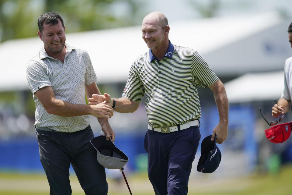 Robert Garrigus, left, congratulates Tommy Gainey on the 18th hole, after finishing their round for the day, during the first round of the PGA Zurich Classic golf tournament at TPC Louisiana in Avondale, La., Thursday, April 21, 2022. (AP Photo/Gerald Herbert)