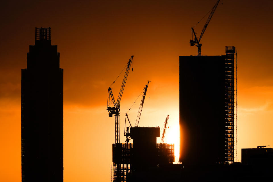 The sun rises behind tower blocks under construction in London as the clocks move forward an hour to British Summer Time (BST).