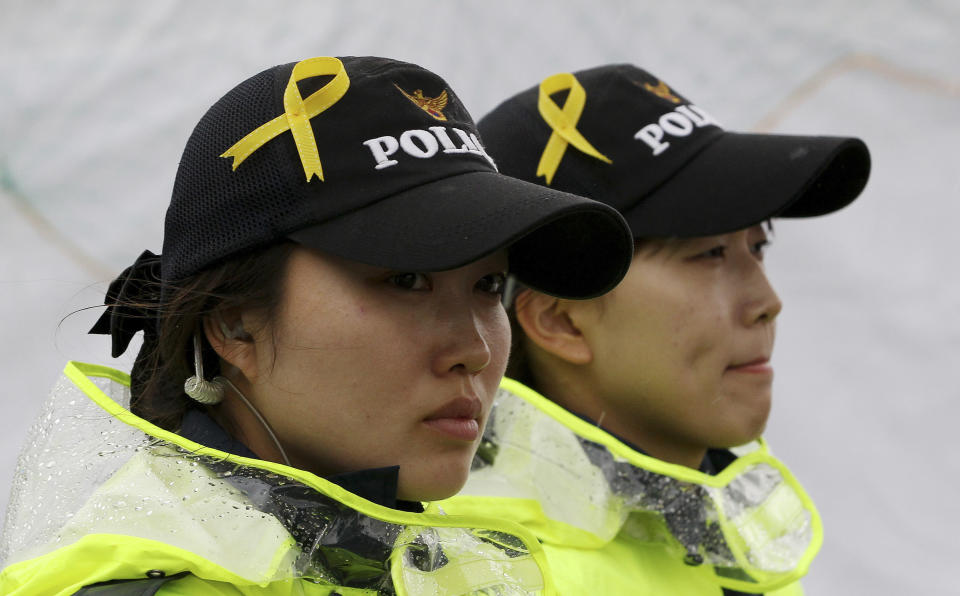 Yellow ribbons as a sign of hope for the safe return of missing passengers of the sunken ferry Sewol are pinned on caps of police officers at a port in Jindo, South Korea, Sunday, April 27, 2014. South Korea's President Park Geun-hye accepted her Prime Minister Chung Hong-won's resignation Sunday over the government's handling of a deadly ferry sinking, although she didn't set a last day in office. (AP Photo/Ahn Young-joon)