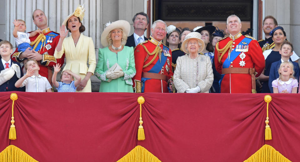 Royal family stand and look up on balcony.