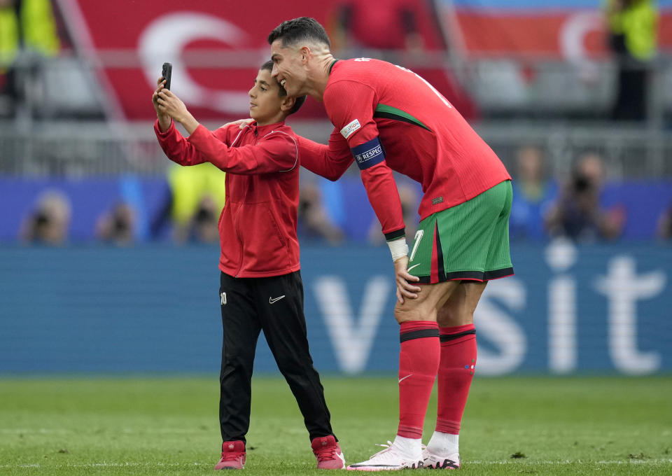 A young pitch invader takes a selfie with Portugal's Cristiano Ronaldo during a Group F match between Turkey and Portugal at the Euro 2024 soccer tournament in Dortmund, Germany, Saturday, June 22, 2024. (AP Photo/Themba Hadebe)