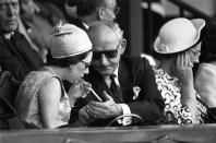 <p>Princess Margaret lights her cigarette while seated in the Royal Box.</p>